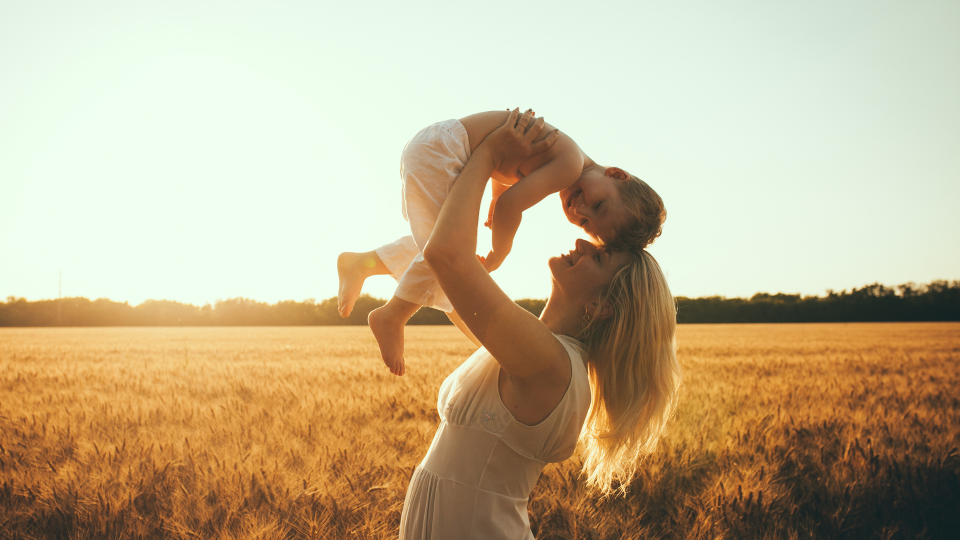 How To Create a Vision for Your Dream Business: Aligning Your Personal and Financial Goals For Success this is a mama outside with her baby holding her up lovingly to her head